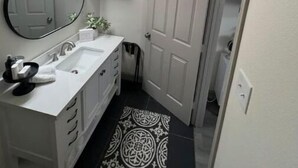 A small bathroom with a white sink, a mirror, and a door.