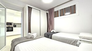 A hotel room with two beds, a kitchenette, and a sliding door leading to a balcony. - Heart of Los Cristianos,Heated Pool (Los Cristianos)