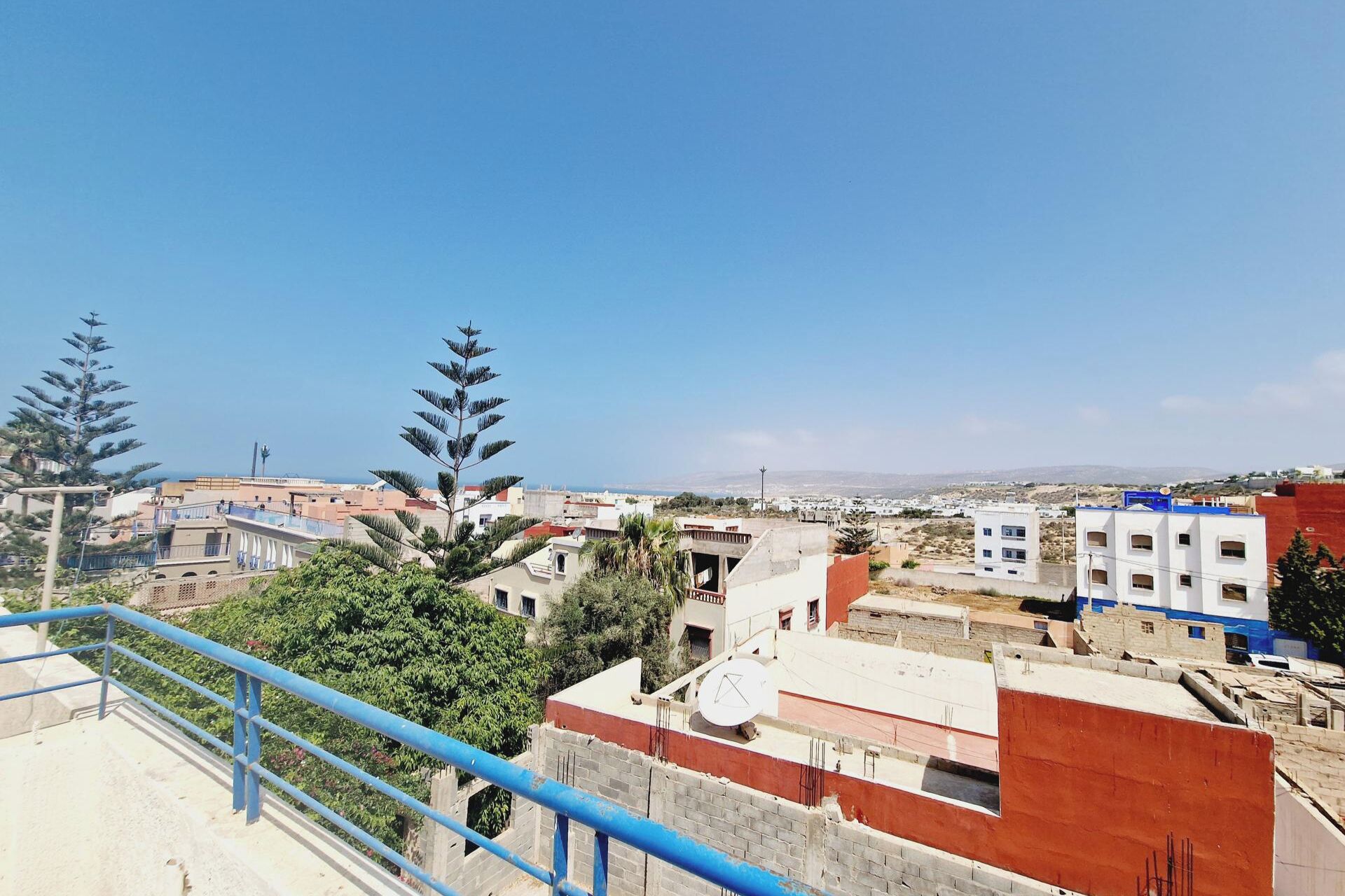 A residential area with buildings, a satellite dish, and a clear blue sky.