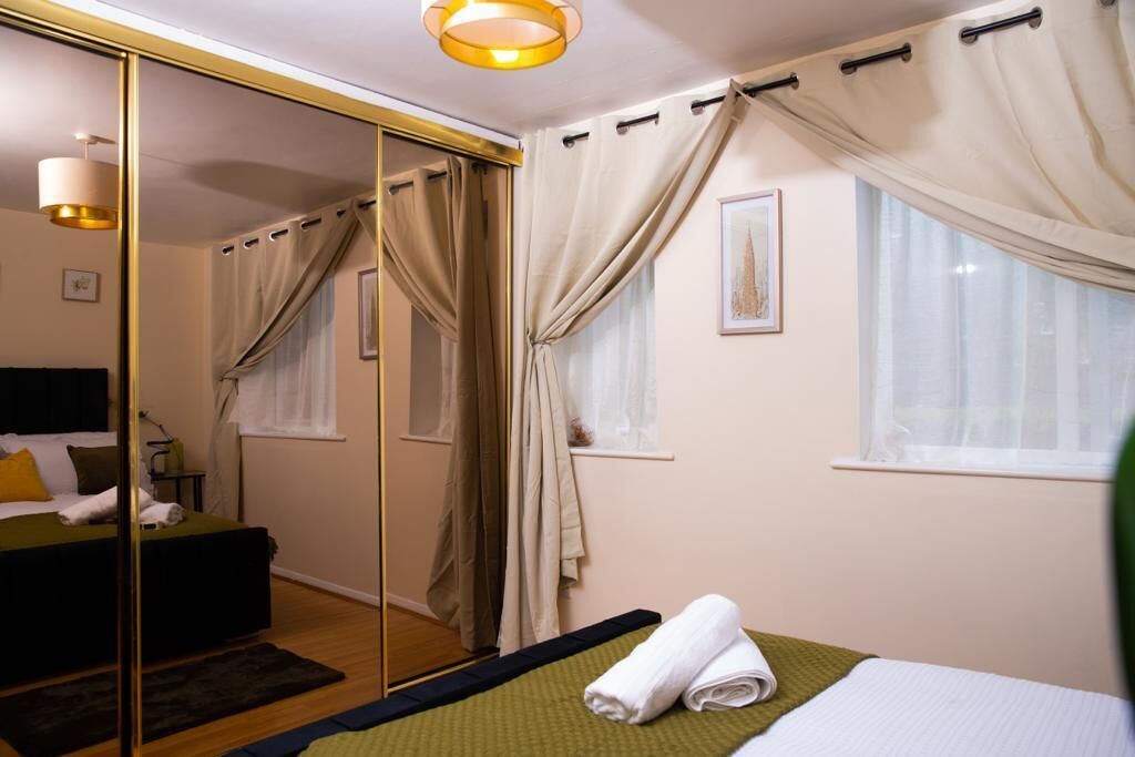 Une chambre d’hôtel avec un lit, un miroir, une fenêtre avec des rideaux et une table de chevet.