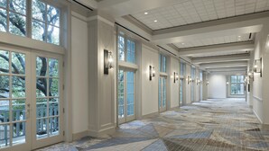 A hotel corridor with large windows, a patterned floor, and wall sconces. - 1-Bedroom Suite at a 4⭐️ Hotel (San Antonio)