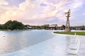 Um imóvel à beira-mar com piscina, cadeiras de descanso e uma construção alta com uma bandeira.