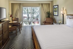 A hotel room with a large bed, a desk with a chair, a television, and a window with curtains. - 1-Bedroom Suite at a 4⭐️ Hotel (San Antonio)