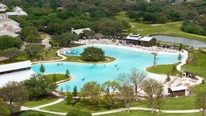 A large outdoor swimming pool surrounded by a park with walking paths, a golf course, and a lake. - 1-Bedroom Suite at a 4⭐️ Hotel (San Antonio)