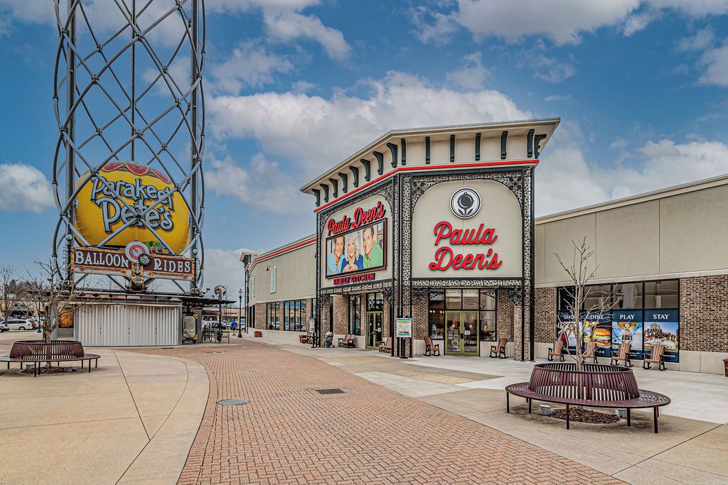 A Paula Dees restaurant with a large sign, a parking lot, and a balloon ride attraction in the background.