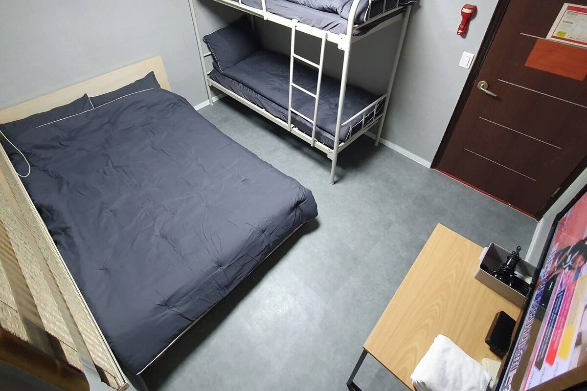 A bunk bed room with a desk and a door.