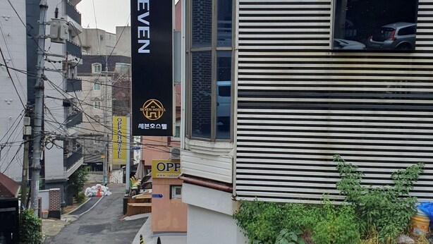 Um edifício com uma placa que indica 'SEVEN HOSTEL' e outra placa que indica 'OPPAA'.