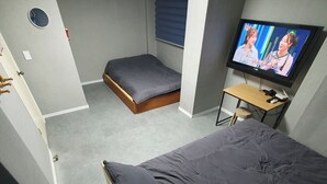 Quarto com cama, um espaço de estar pequeno, televisão e janela.
