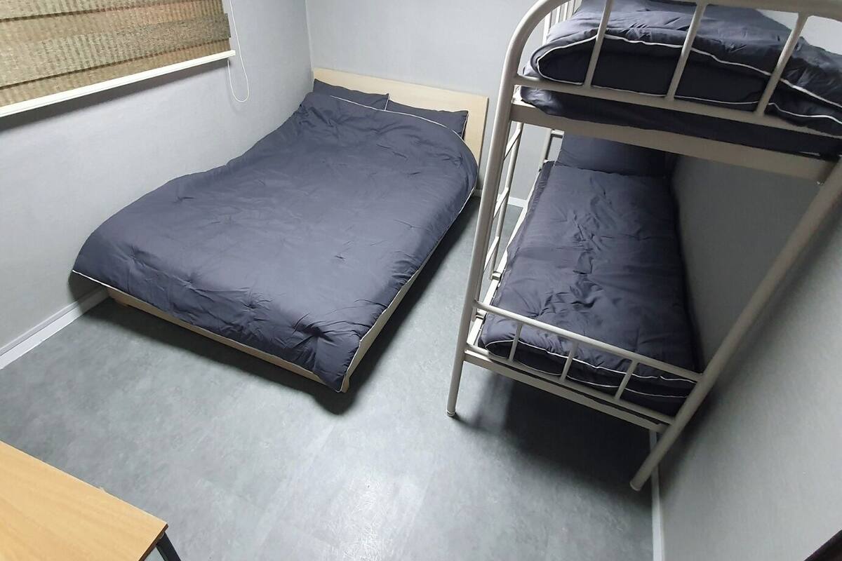A bunk bed room with a single bed and a desk.