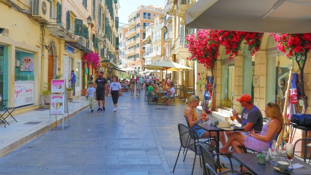 A bustling street with outdoor seating at cafes, a variety of shops, and a clear pedestrian pathway. - Casa di Marina in Corfu (Corfu)