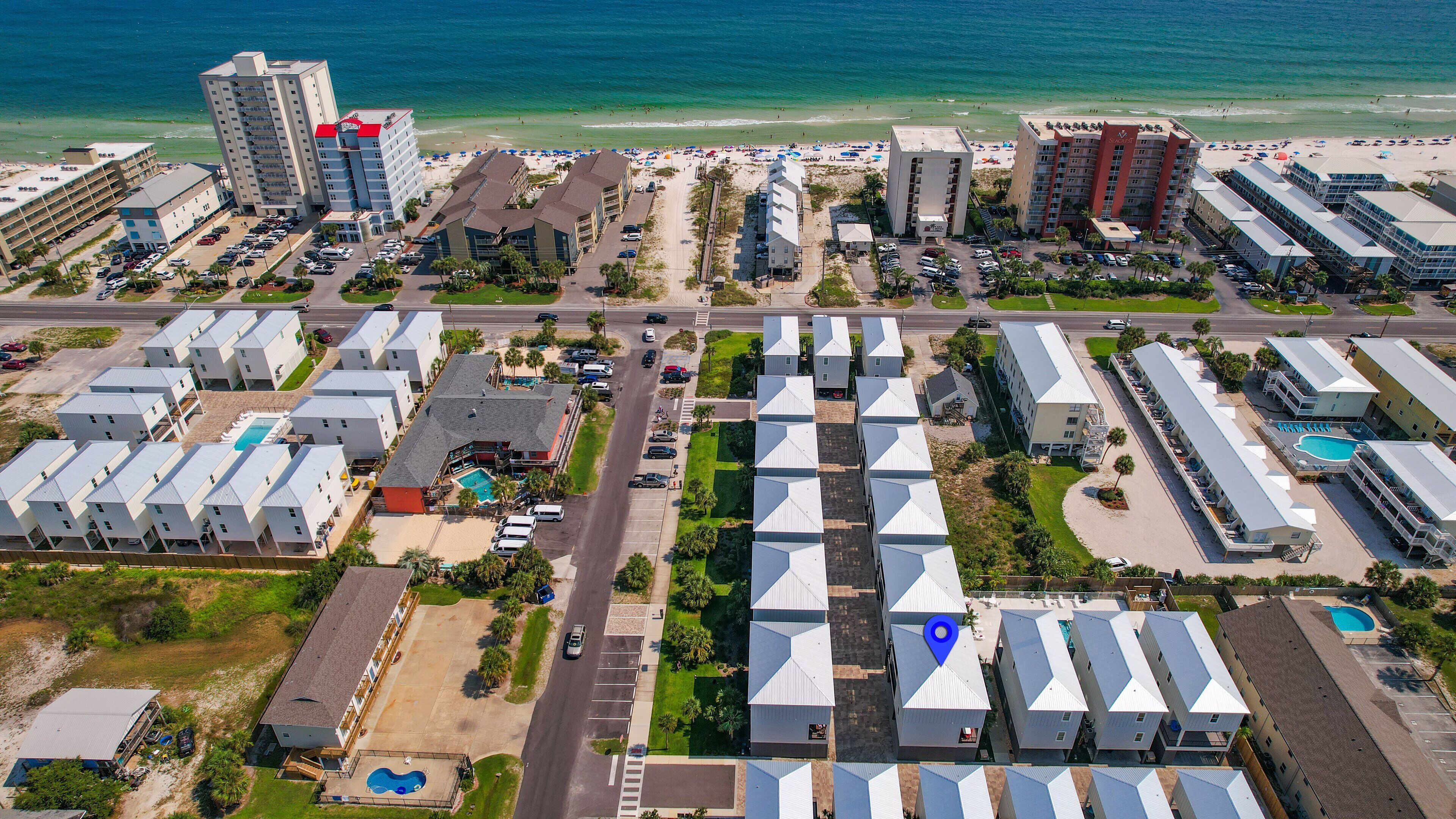 Un complexe hôtelier situé sur la côte, composé de plusieurs bâtiments, doté d’une piscine et offrant une vue sur la plage.