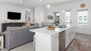 A modern kitchen with a central island, white cabinetry, and a built-in dishwasher. - The Hive a one-minute walk to the beach! Two community pools & nearby Lagoon access (Gulf Shores)
