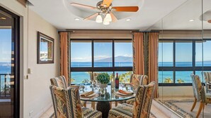Un coin repas avec une table en verre, des chaises à motifs et une vue sur l’océan.