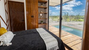 Un dormitorio con una cama grande, un armario de madera, estanterías y vistas a una piscina.