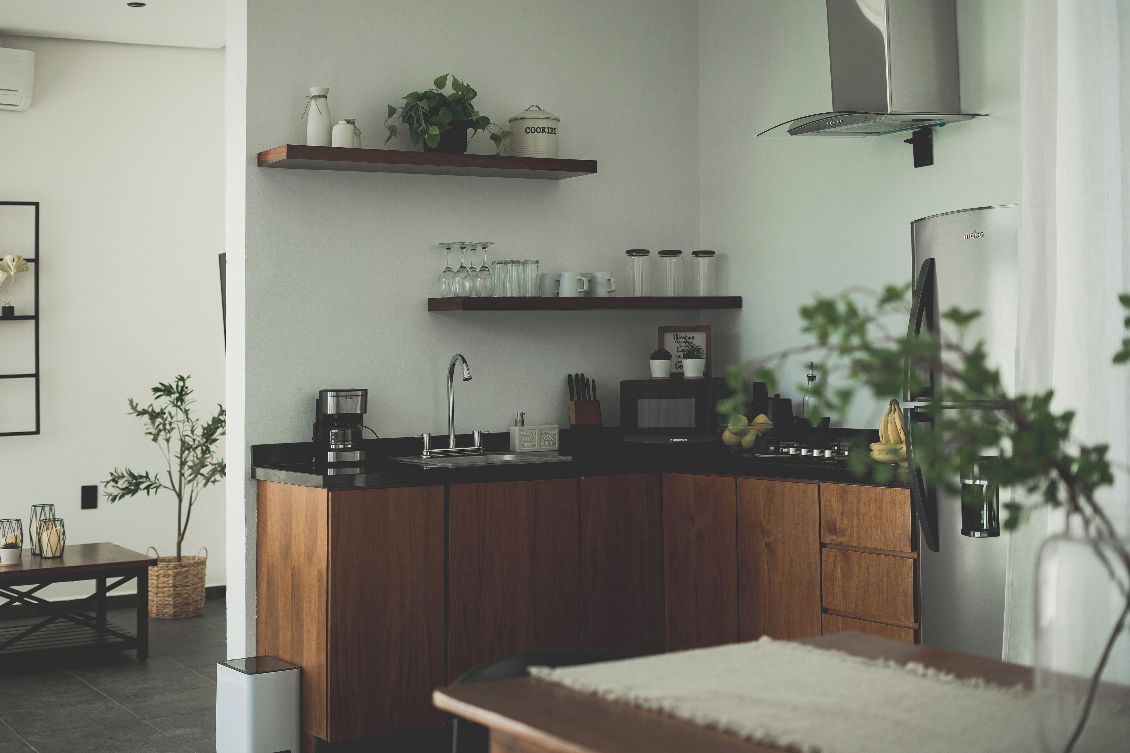 Una cocina moderna con armarios de madera, electrodomésticos de acero inoxidable y estantes de madera con utensilios de cocina.