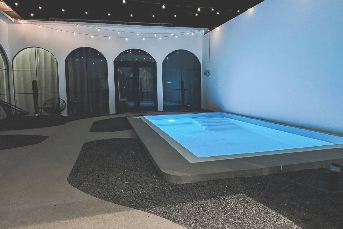 A modern interior with a central pool, arched doorways, and string lights.
