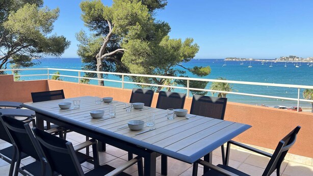 An outdoor dining area with a table and chairs, overlooking a coastal view with boats and trees. - Apartment with air co and breathtaking sea view and direct beach access for 6 (SANARY SUR MER)