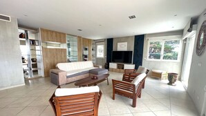 A living room with a sofa, two wooden chairs, a coffee table, a TV, and a bookshelf. - Apartment with air co and breathtaking sea view and direct beach access for 6 (SANARY SUR MER)