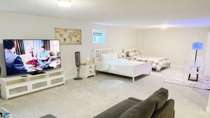 Una sala moderna con televisor, sofá, cama y mesita de noche.