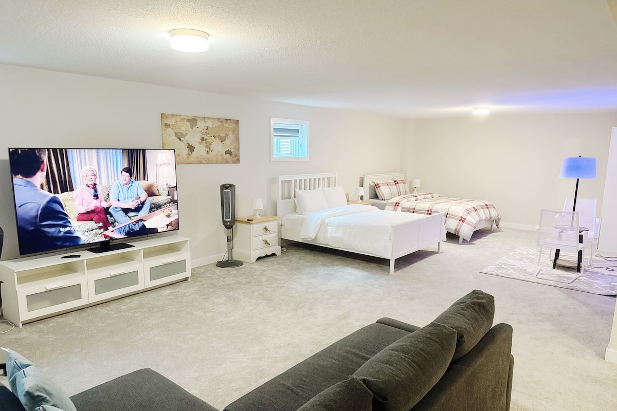 A modern living room with a TV, a sofa, a bed, and a bedside table.