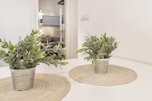 Two potted plants on a white surface with woven placemats. - Sardinia Re - Casa Pinuccia (Alghero)