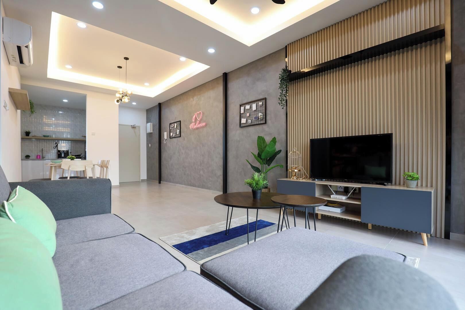 Una sala de estar moderna con un sofá gris, una mesa de centro, un televisor y un comedor al fondo.