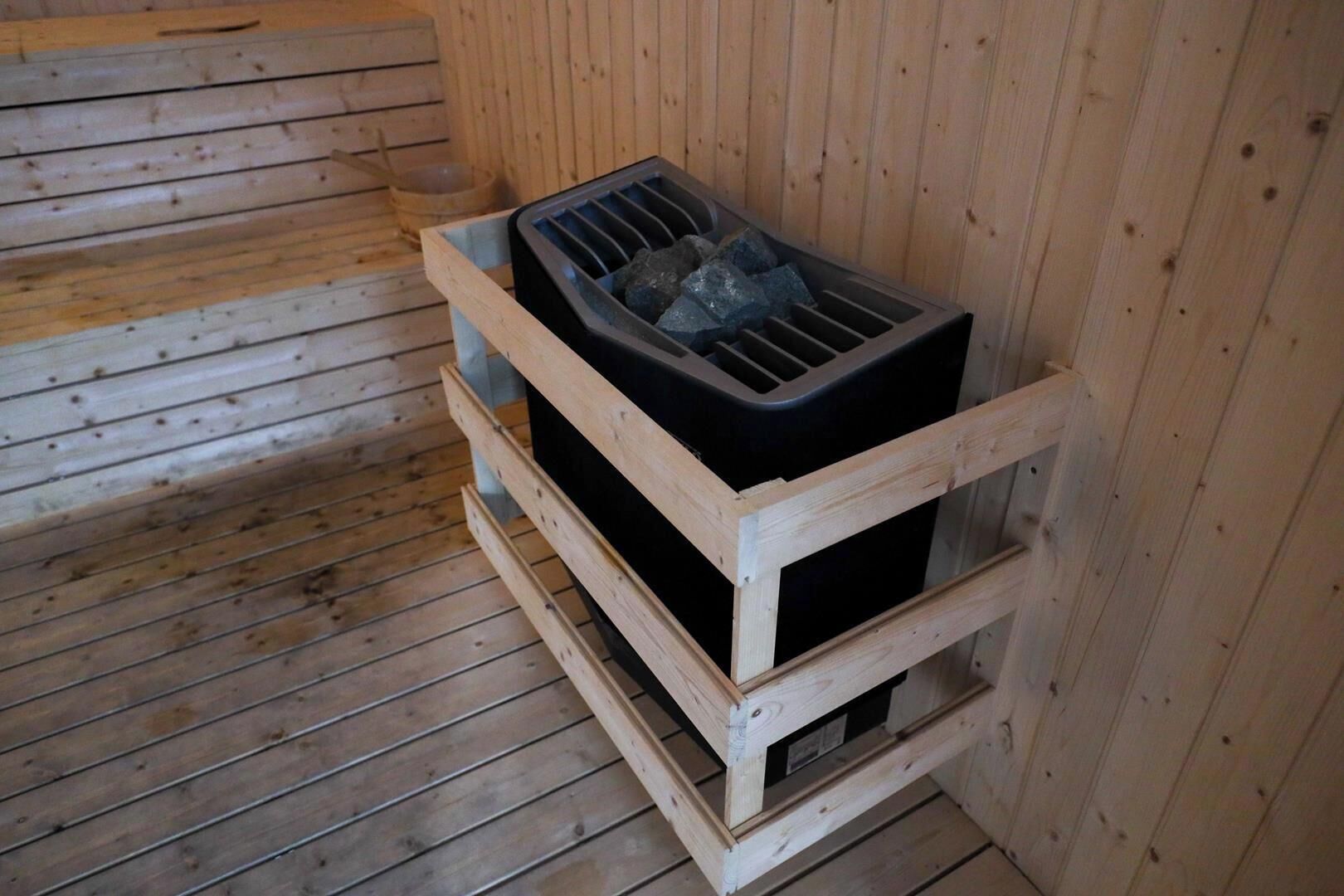 Una sauna con estructura de madera y un calentador negro.
