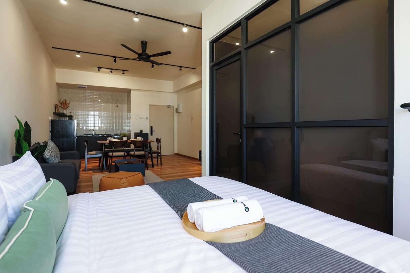 A modern hotel room with a bed, a dining area, and a large sliding glass door.