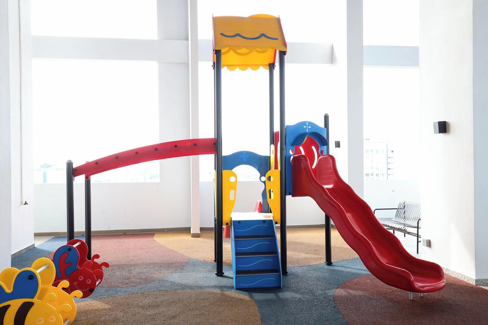Ein Kinderspielbereich mit Rutsche, Klettergerüst und bunten Spielsachen.