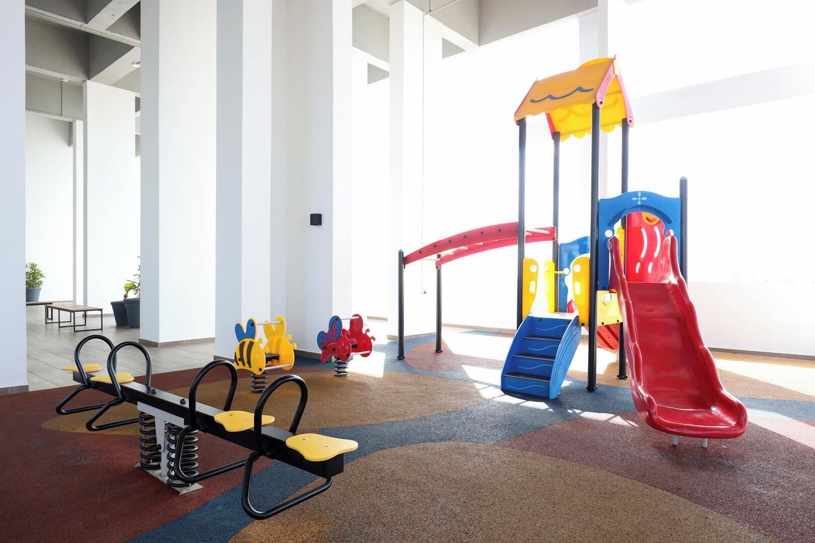 A children's play area with a seesaw, climbing structures, and a slide.