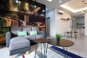 Een moderne woonkamer met een modulaire bank, een ronde salontafel en een eethoek met een tafel en stoelen.