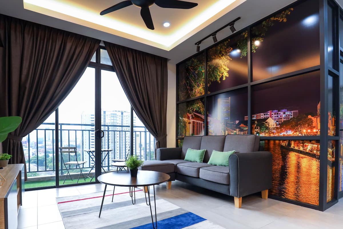 A modern living room with a sofa, a coffee table, and a view of a cityscape through large windows.