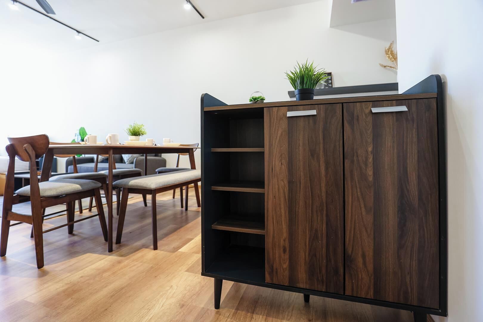 Un interior moderno con un aparador de madera, una mesa de comedor con sillas y una planta en maceta.