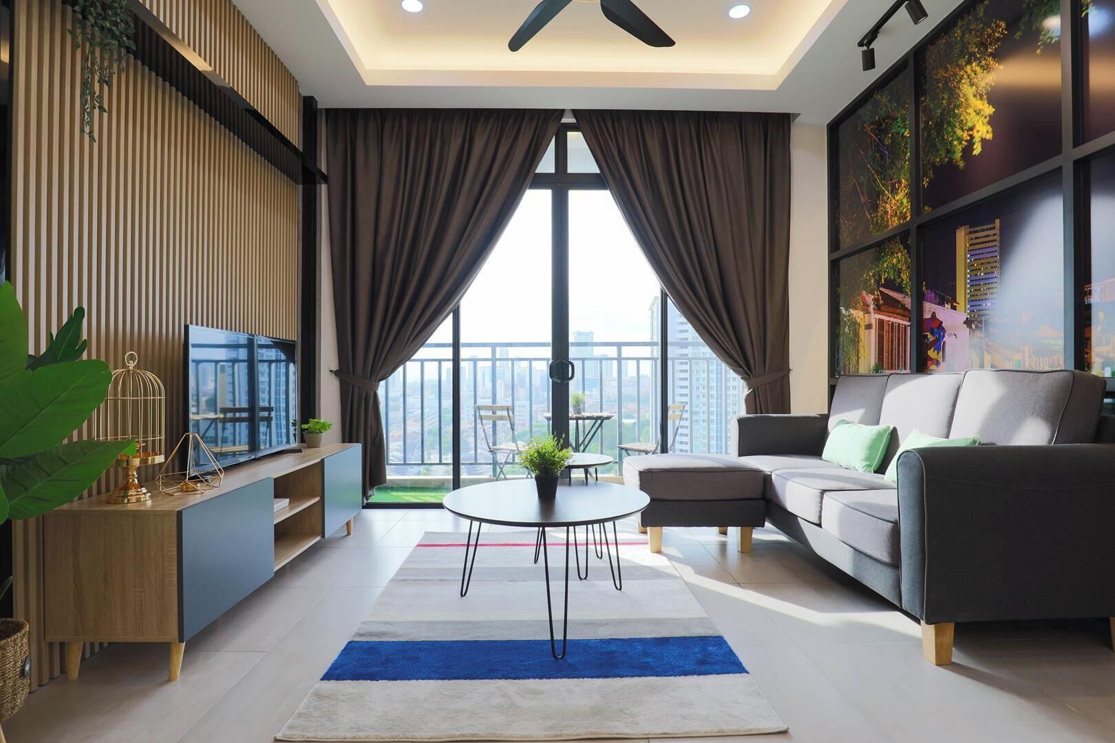 Una sala de estar moderna con un sofá, una mesa de centro y un televisor. Hay un balcón con vistas a la ciudad.
