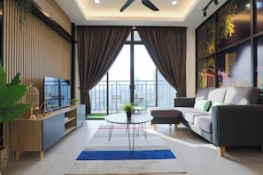 Een moderne woonkamer met een bank, een salontafel en een televisie. Er is een balkon met uitzicht op de stad.