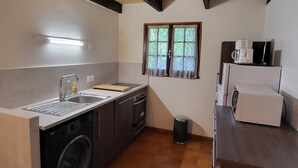 Cocina compacta con lavadora, un lavabo y una ventana con cortinas estampadas.