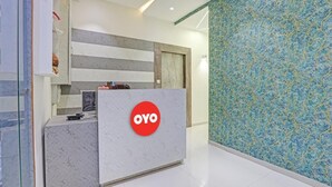 A reception desk with a marble finish and a red logo, a patterned wall, and a door with a handle. - Hotel Planet Villa (Ahmedabad)