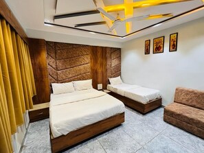 Un dormitorio moderno con dos camas, un cabecero de madera, un sofá marrón y un techo con lámpara de diseño geométrico.
