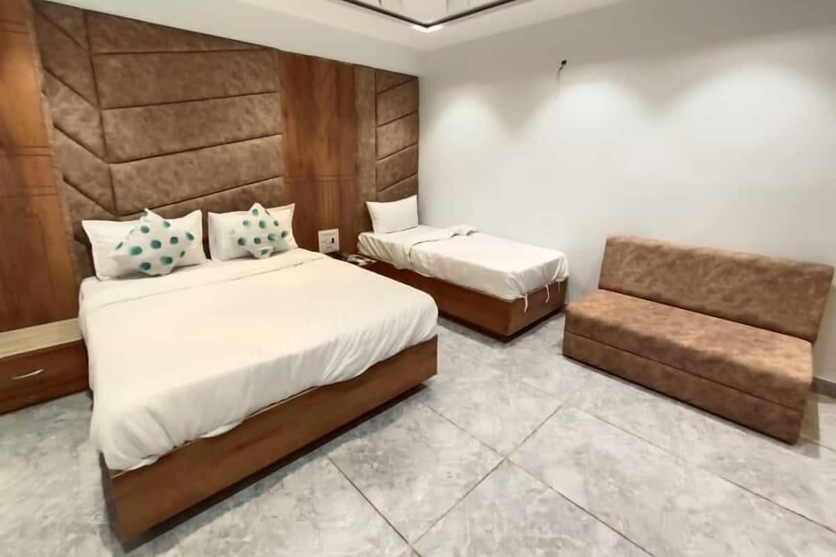 A modern bedroom with a large bed, a smaller bed, and a sofa.