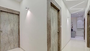 A modern hallway with marble doors and a clean, tiled floor. - Hotel Planet Villa (Ahmedabad)