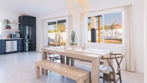 Una cocina moderna con comedor, que incluye una mesa de madera, un banco y una lámpara colgante original.