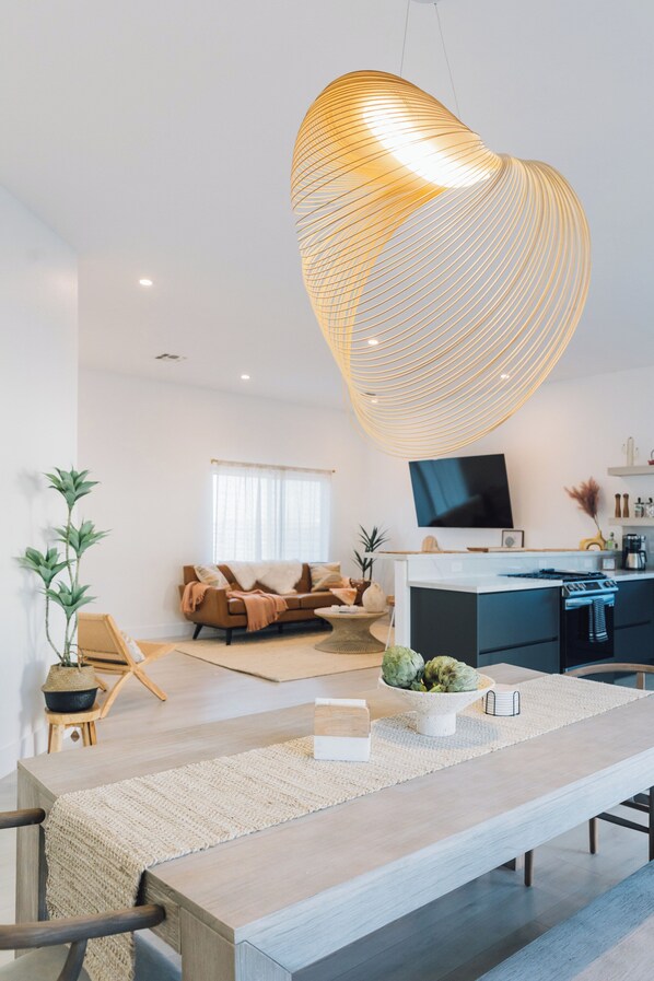 Un salon moderne avec une grande table à manger en bois, un canapé et un téléviseur.