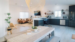 Cocina moderna con una isla central, electrodomésticos integrados y una zona de comedor con banco y mesa.