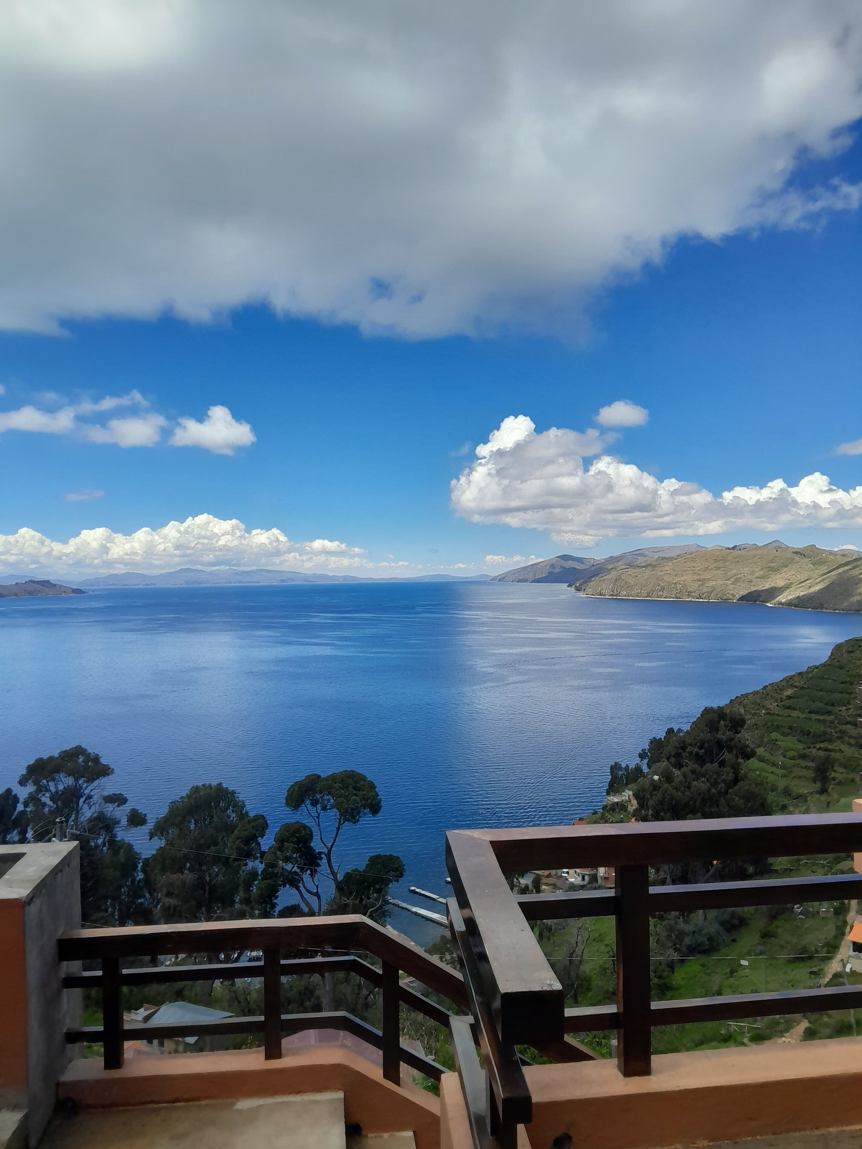 Vista panorámica desde un balcón con vista a una extensa masa de agua, montañas lejanas y cielo despejado.