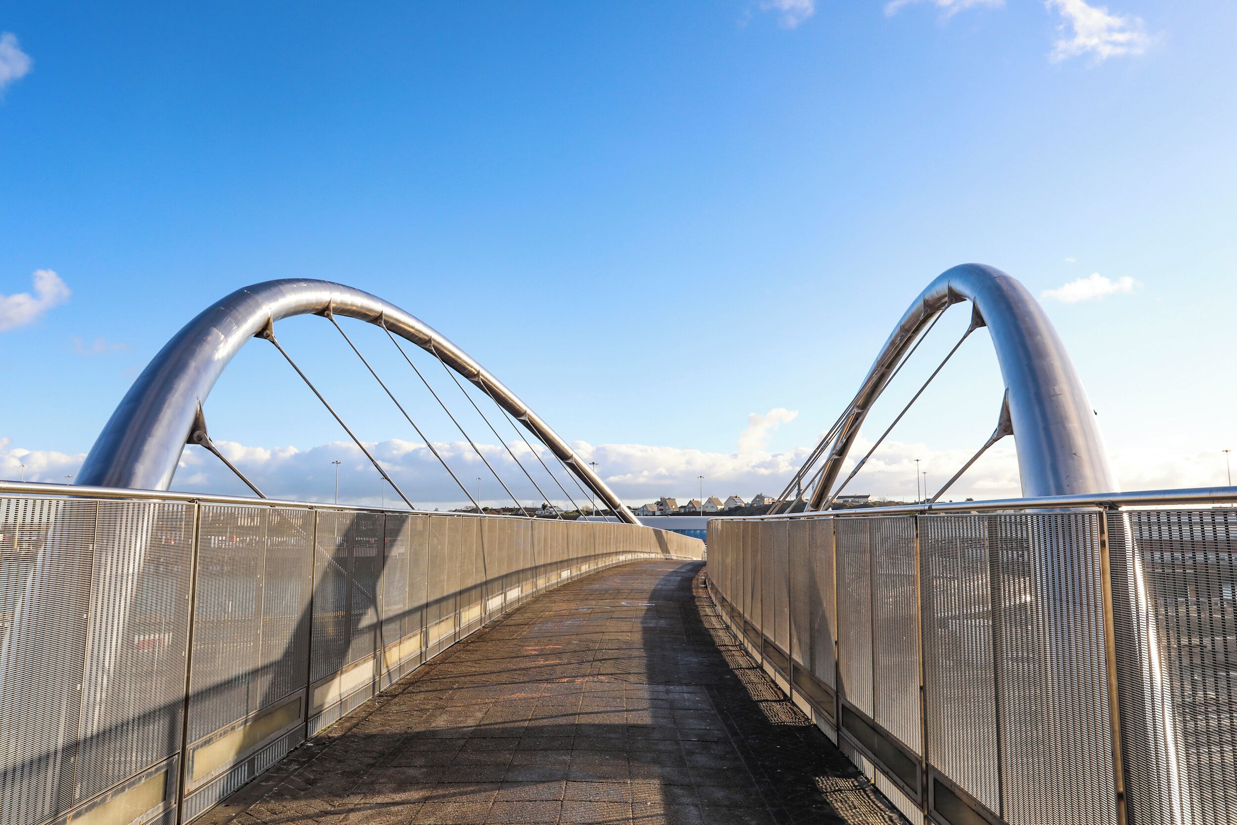 Un pont piétonnier avec des garde-corps en métal et un ciel dégagé.
