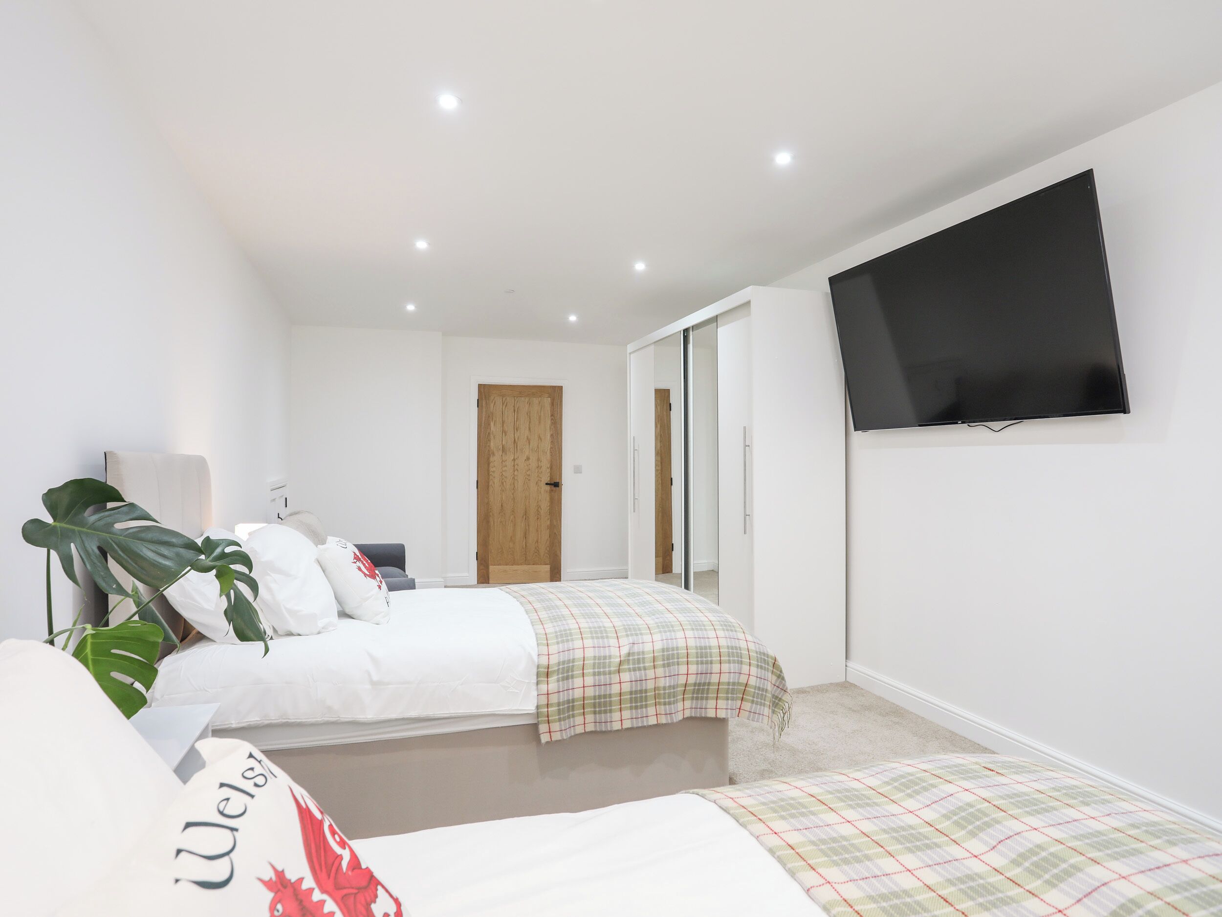 Ein modernes Schlafzimmer mit Bett, Fernseher und Kleiderschrank.