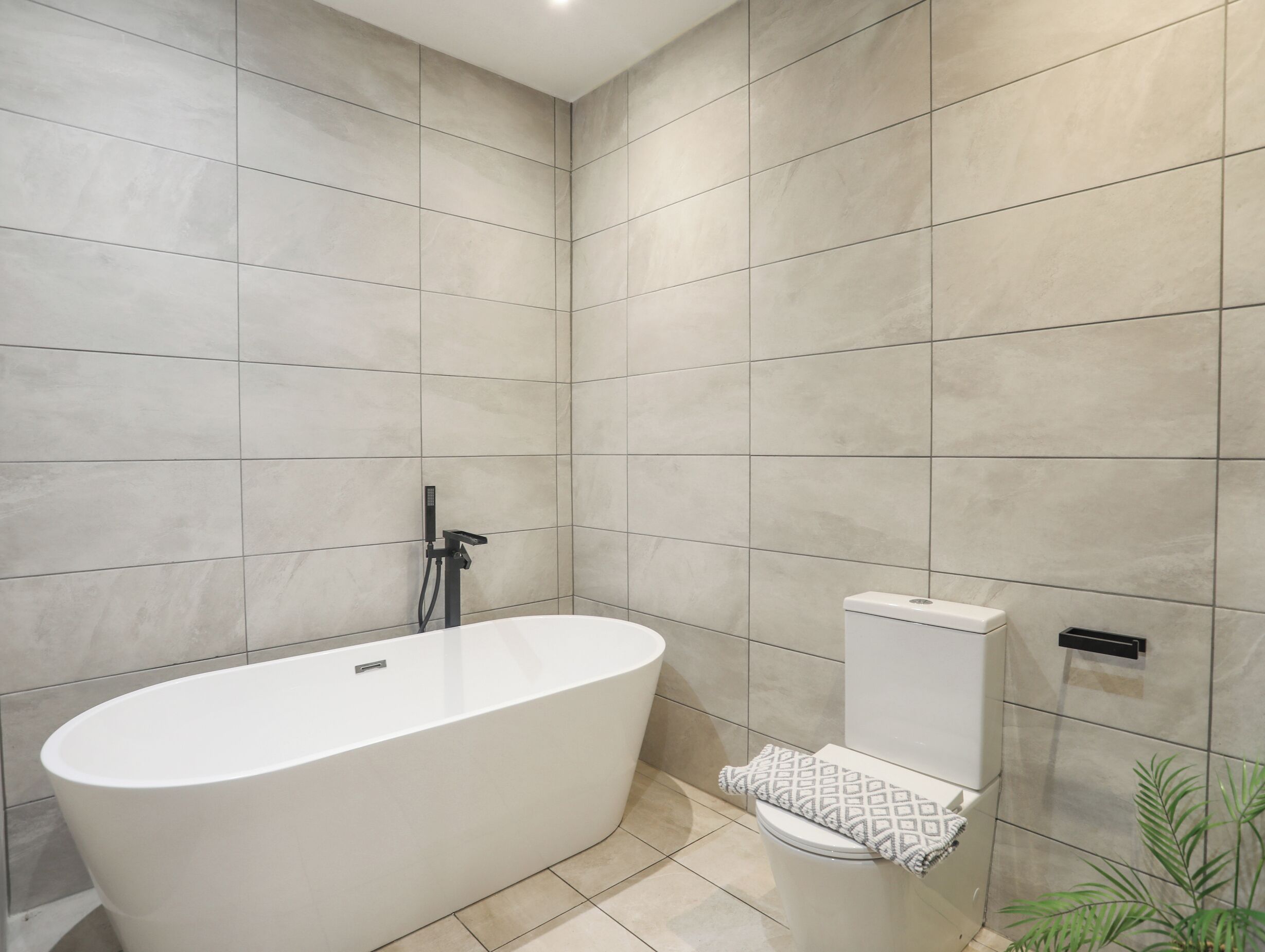 Un baño moderno con una bañera independiente, un inodoro y un cabezal de ducha.