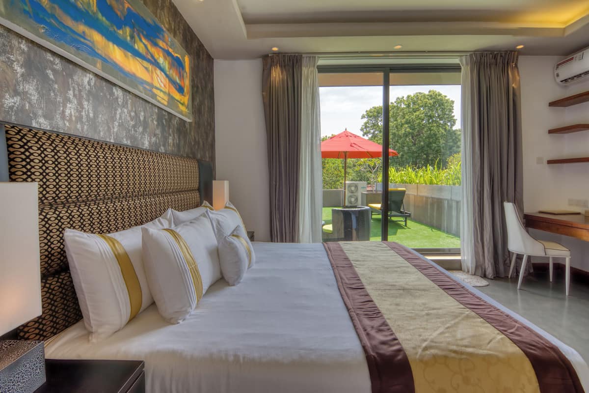 A hotel room with a large bed, a desk, and a view of the outdoors.