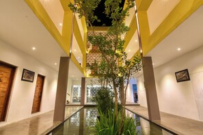 A modern hotel lobby with a glass railing, wooden doors, and a central decorative tree. - Golden Pearl Tangalle Beach (Tangalle)
