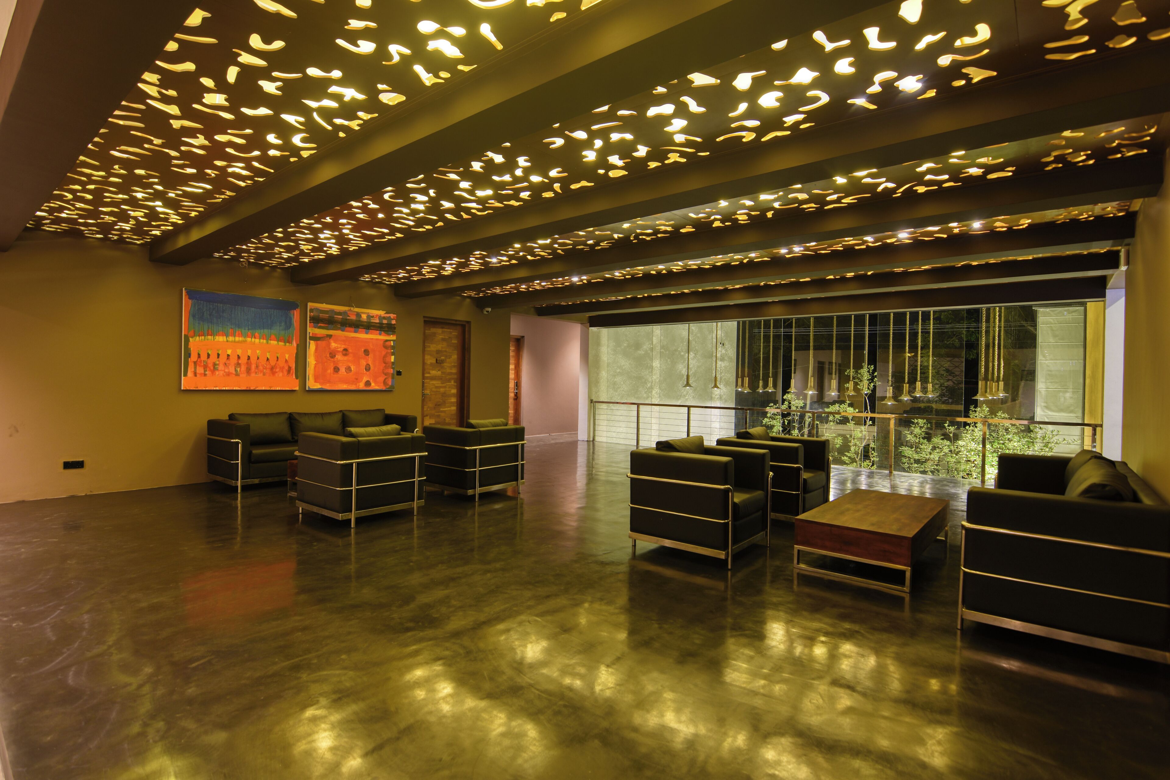 A spacious lobby with modern furniture, large windows, and a unique ceiling design.